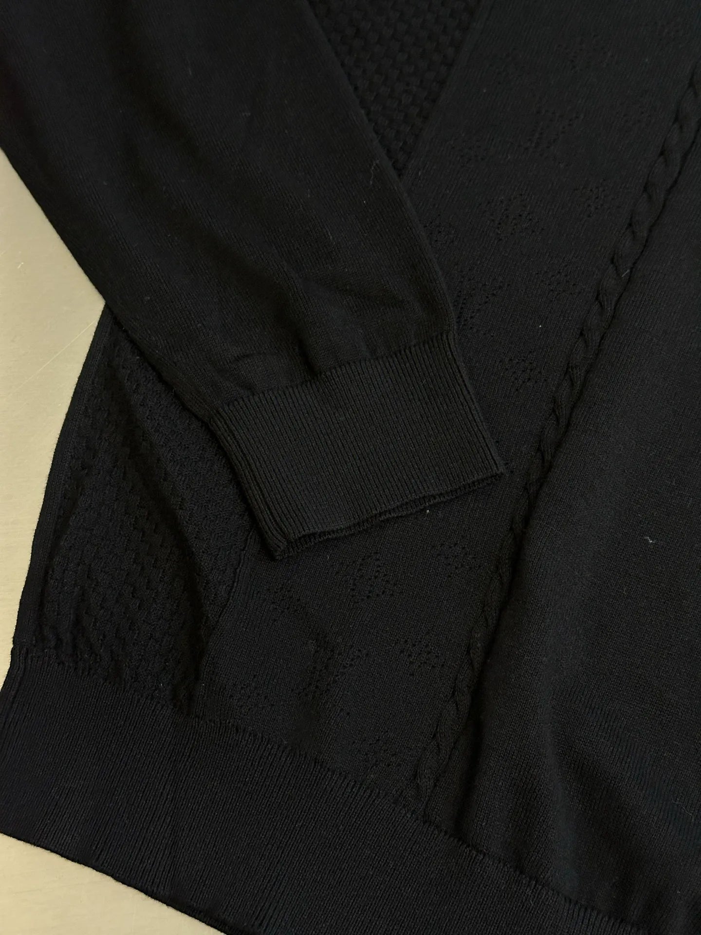 Black sweater with ribbed hem and textured knit paneling detail