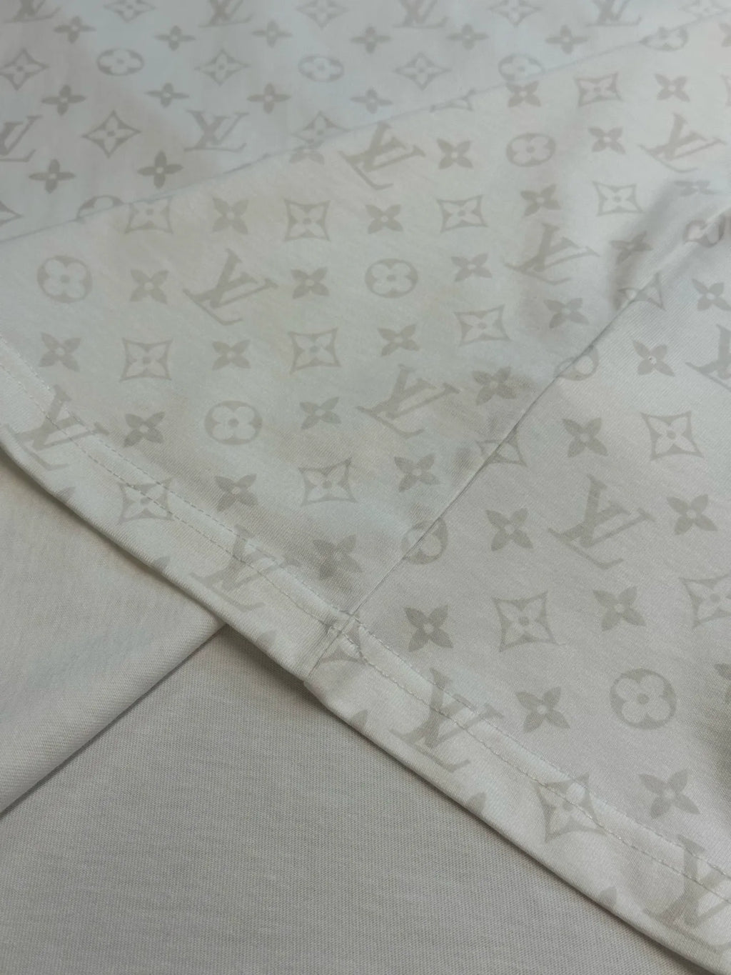 Folded T-shirt fabric with repeating monogram print along hem