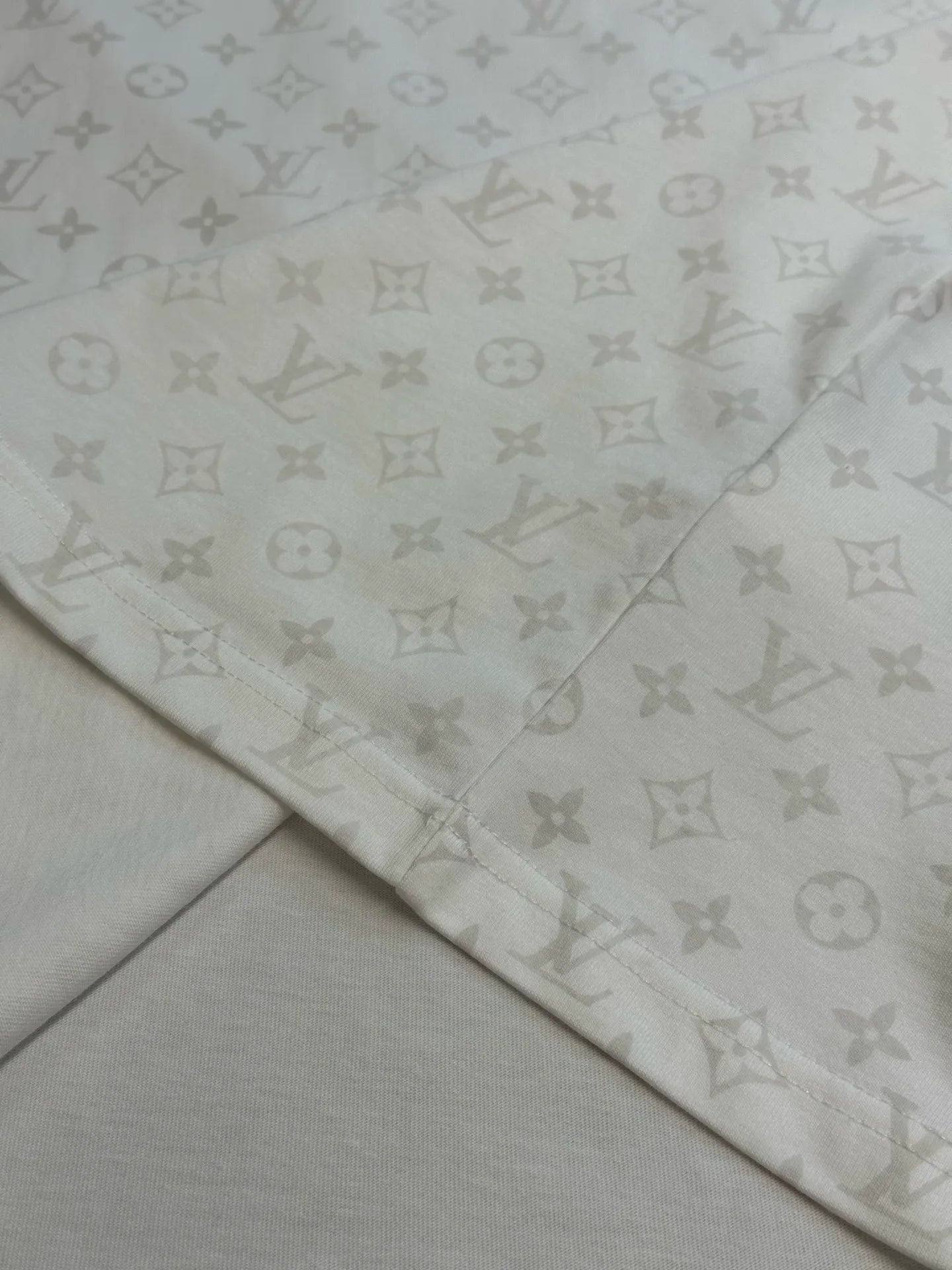 Folded T-shirt fabric with repeating monogram print along hem