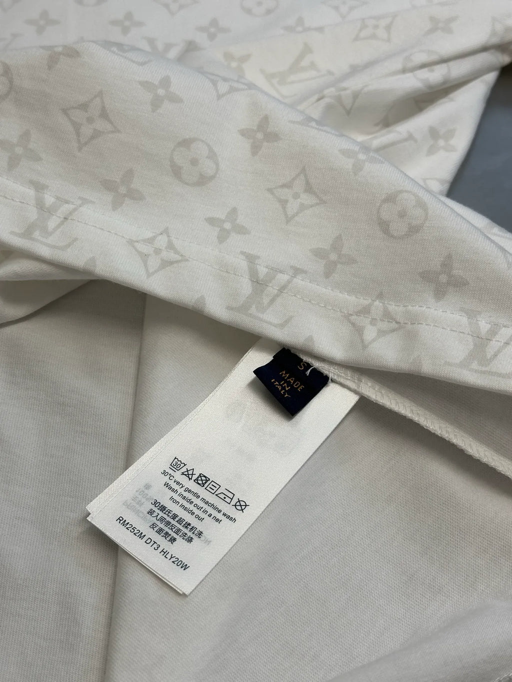 T-shirt hem with size tag and repeating monogram pattern