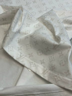 Light-colored T-shirt fabric with repeating monogram pattern, close-up fold