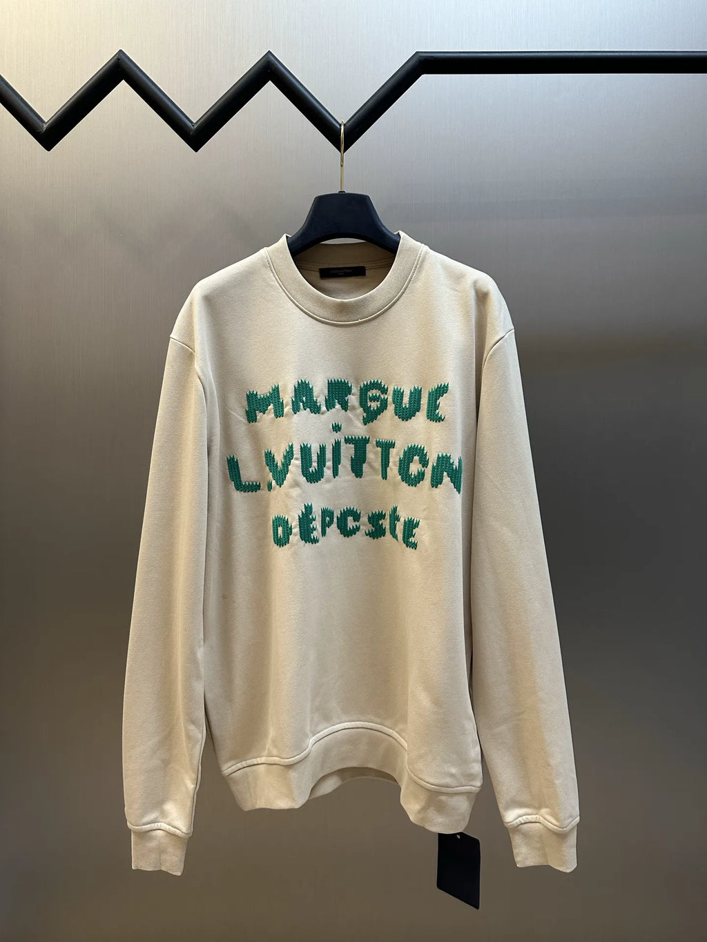 Cream long-sleeve sweatshirt with green LV-style graphic print, crew neck.
