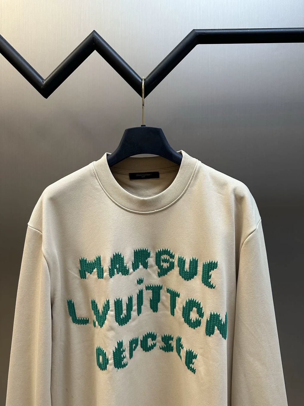 Cream long-sleeve sweatshirt with green graphic lettering across chest, crew neck.