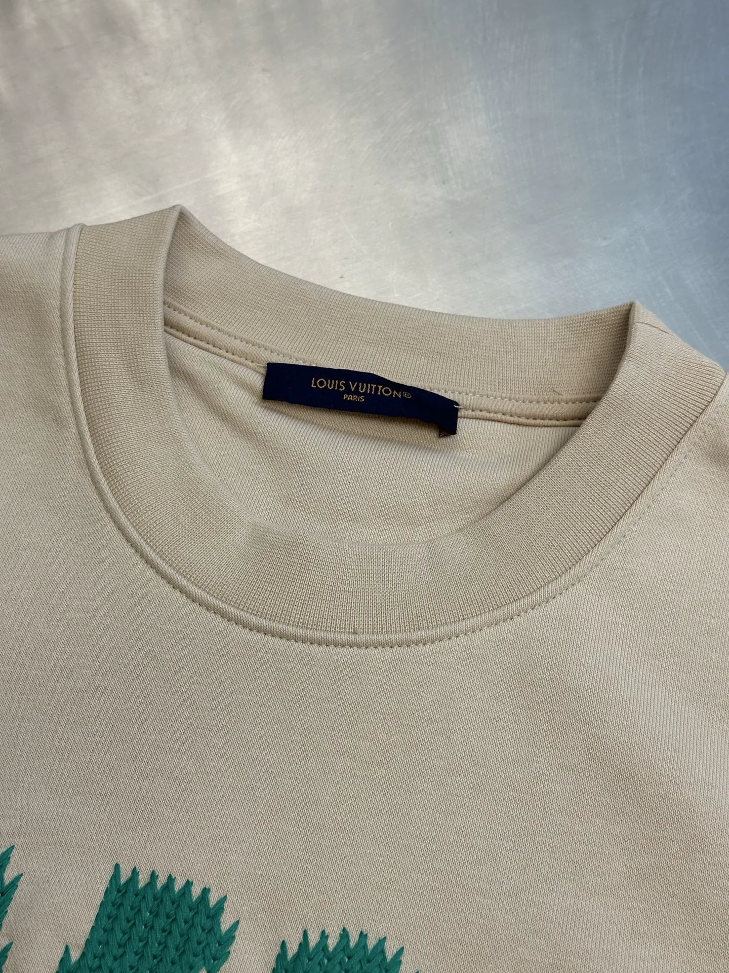 Cream long-sleeve sweatshirt with crew neck and LOUIS VUITTON label tag.