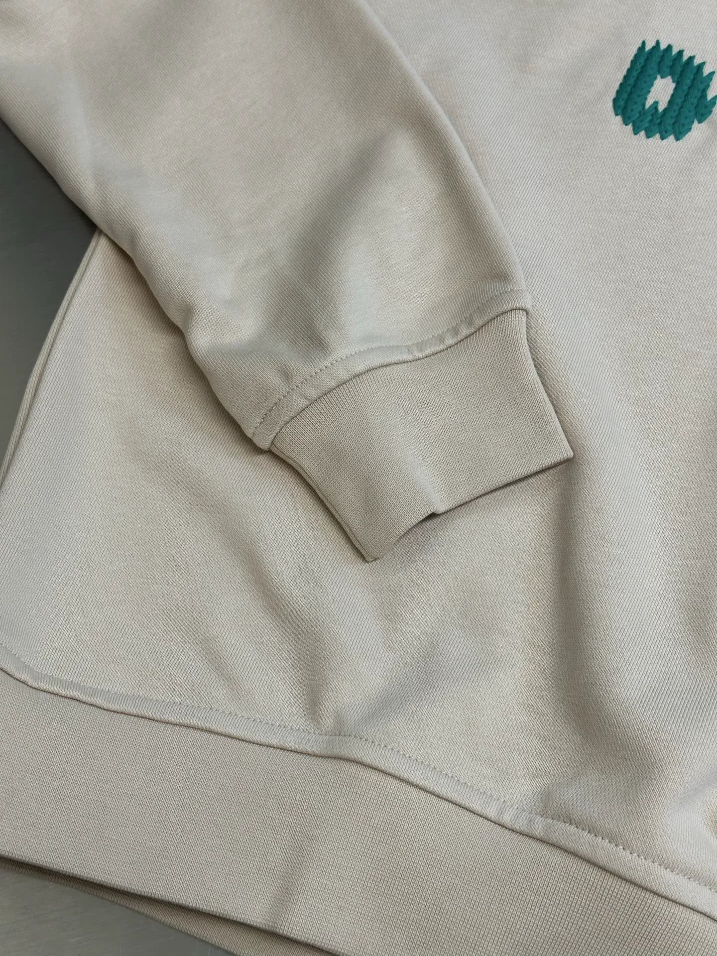 Cream long-sleeve sweatshirt with ribbed cuff and visible seam on sleeve.