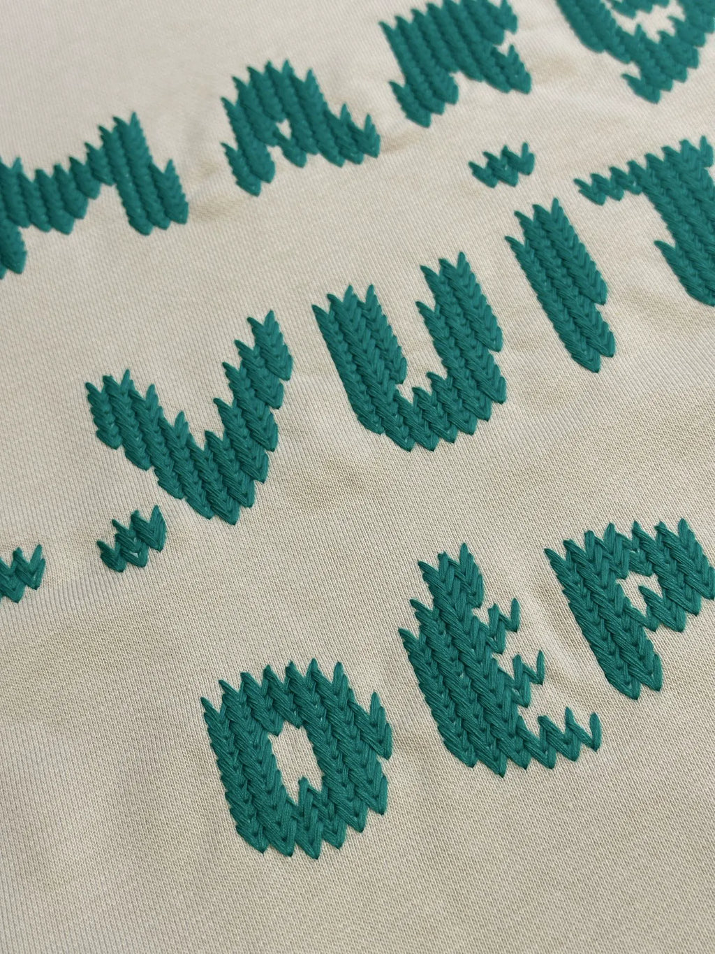 Cream sweatshirt with green stitched lettering graphic detail.