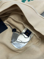 Cream sweatshirt inner neck with navy label and care tag attached by string.