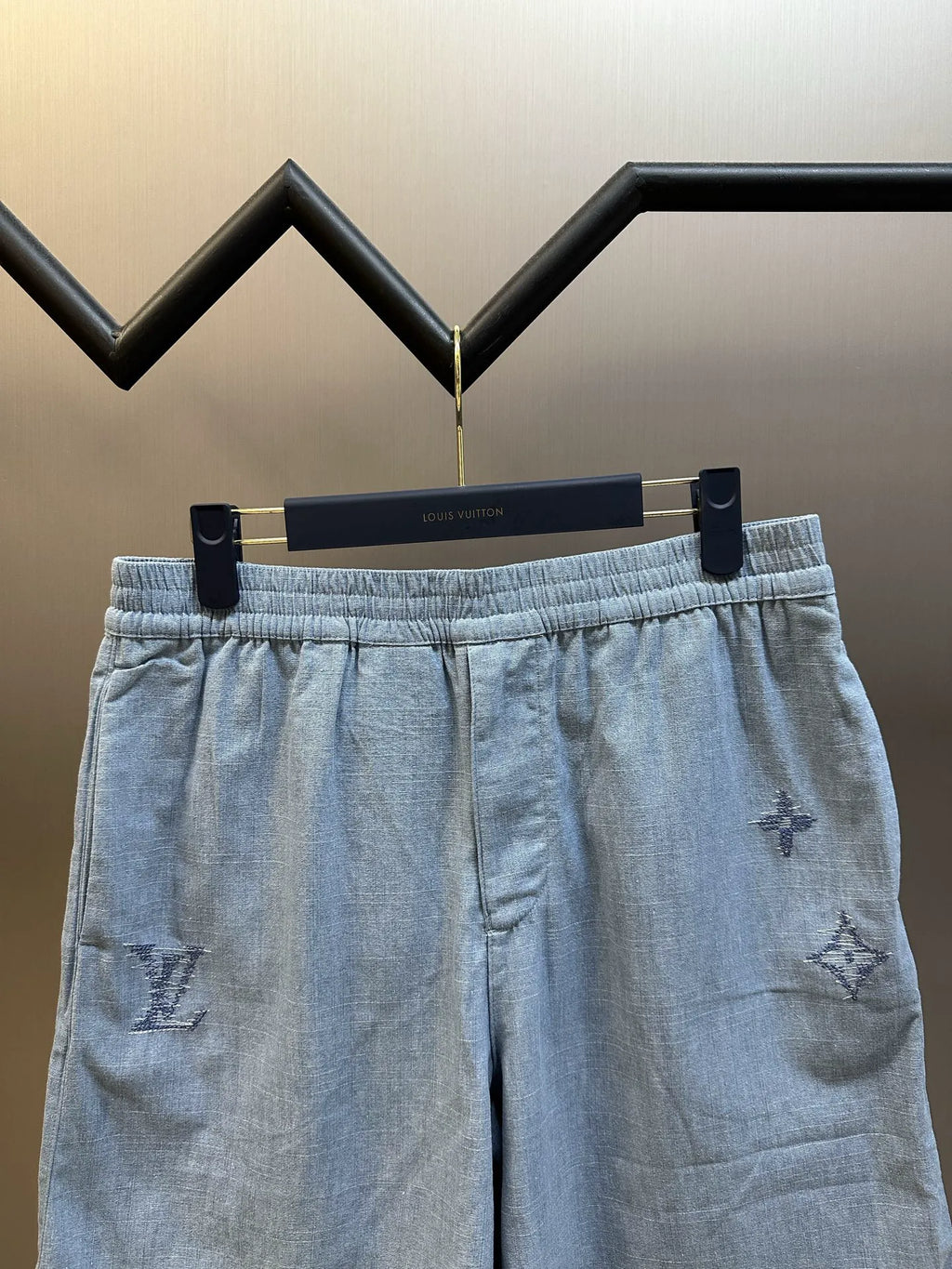 Light blue shorts on hanger, elastic waistband and side pockets with embroidery
