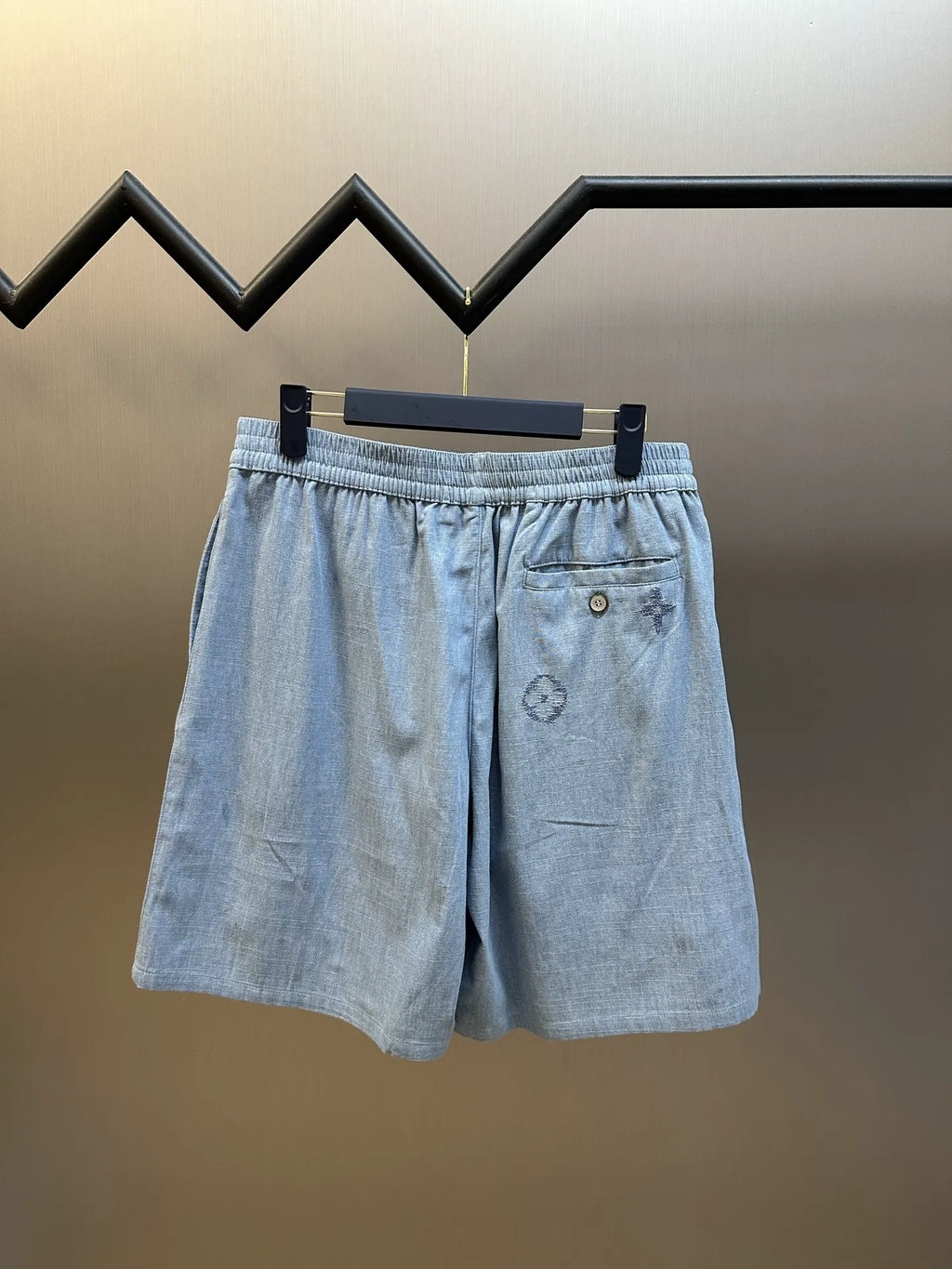 Light blue shorts with elastic waist, front pocket, and embroidered emblem