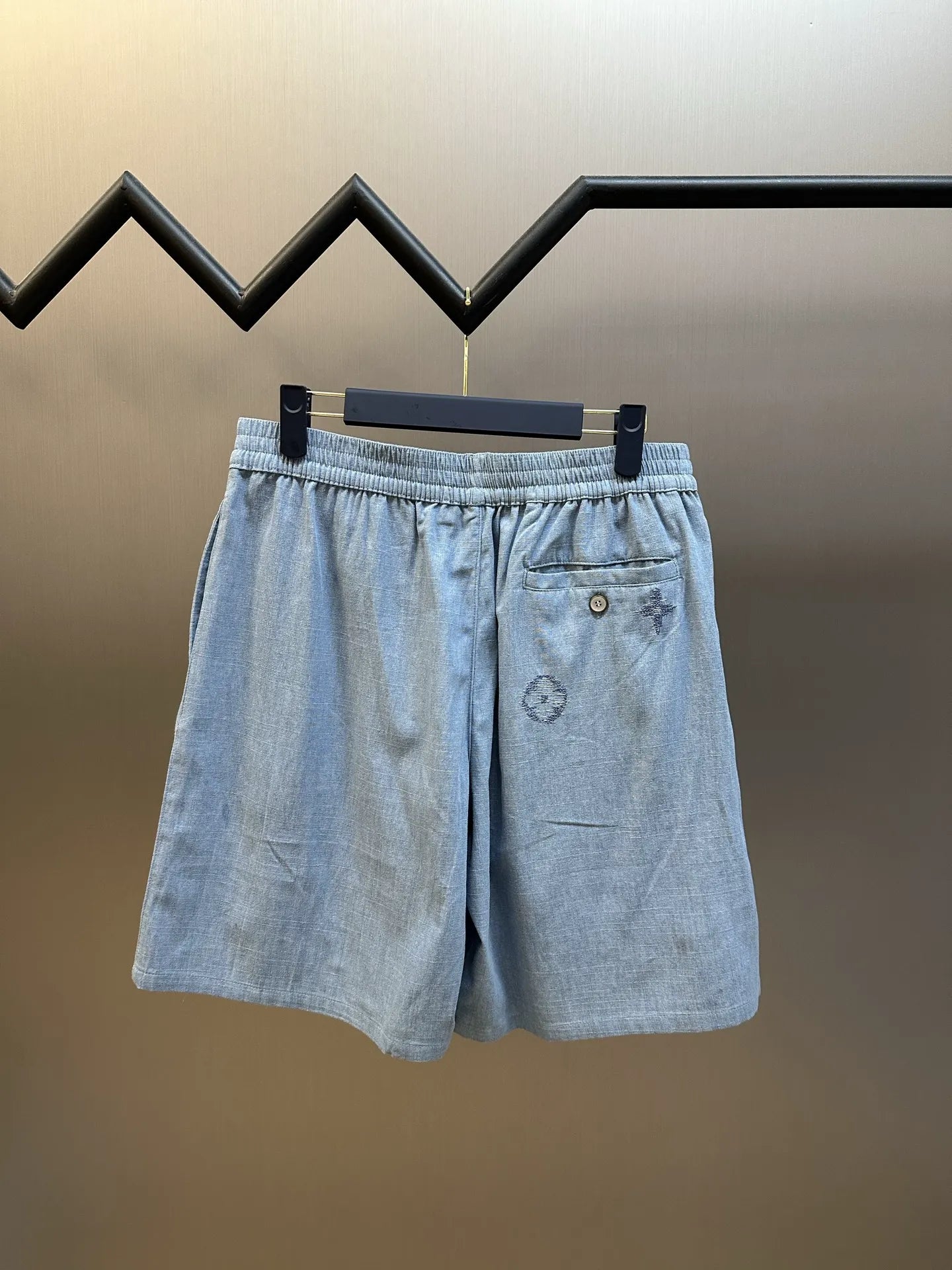 Light blue shorts with elastic waist, front pocket, and embroidered emblem