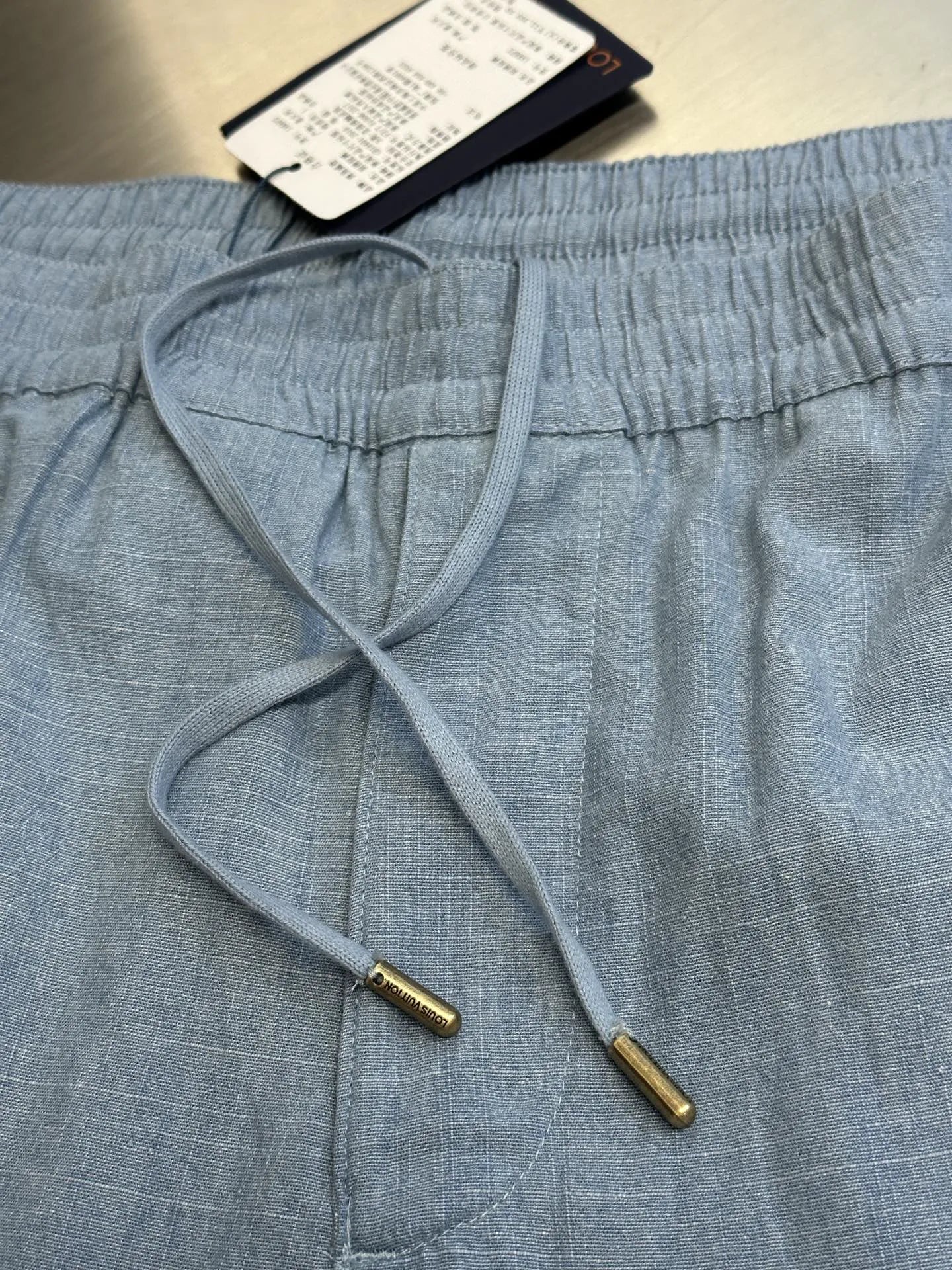 Light blue shorts with drawstring and elastic waist, inside ties visible