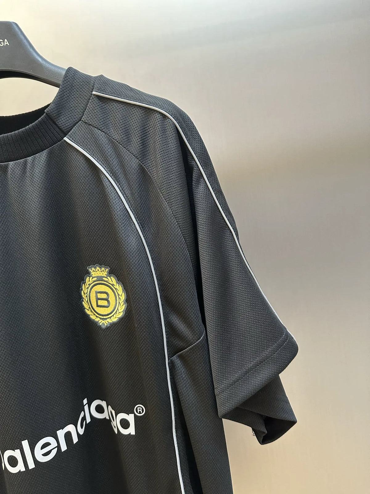 Black Balenciaga athletic jersey detail with yellow crest patch on chest
