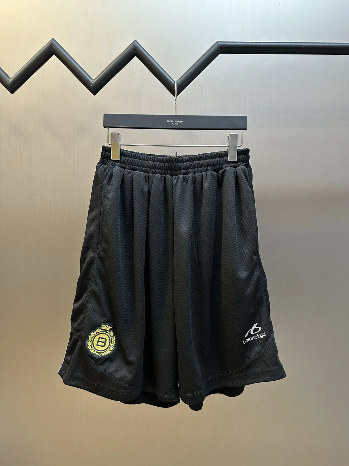 Black elastic-waist shorts with side logo patches and relaxed pleated front