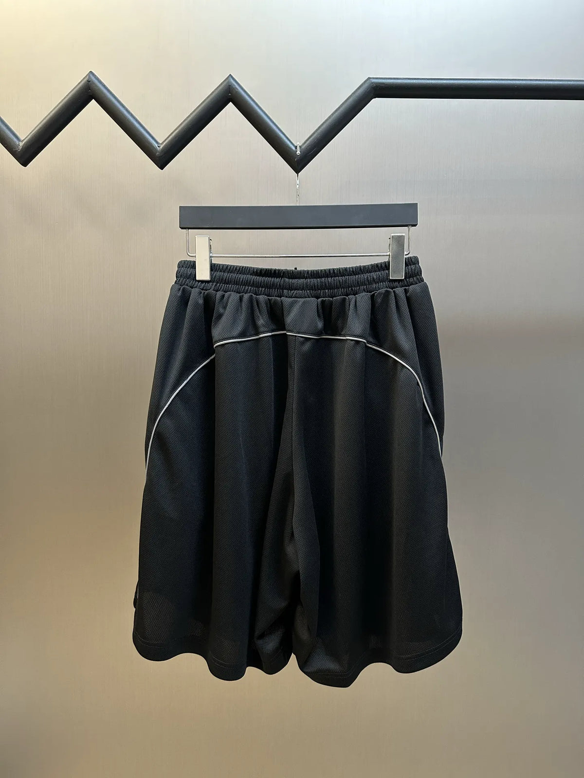 Black elastic-waist shorts with contrast piping and relaxed back drape