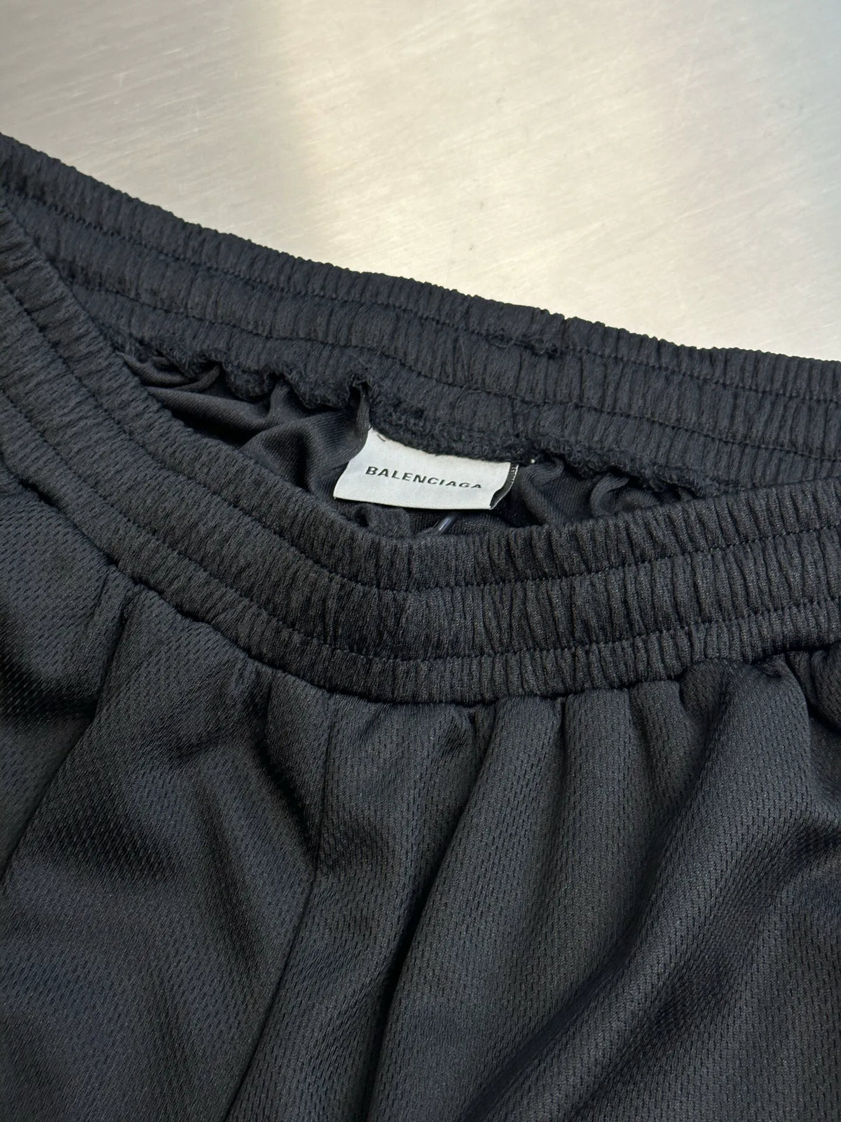 Black elastic-waist shorts with inner brand label and ribbed waistband