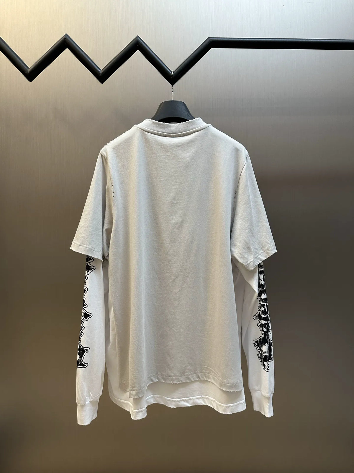 White Balenciaga T-shirt with patterned sleeve cuffs, back view on hanger.