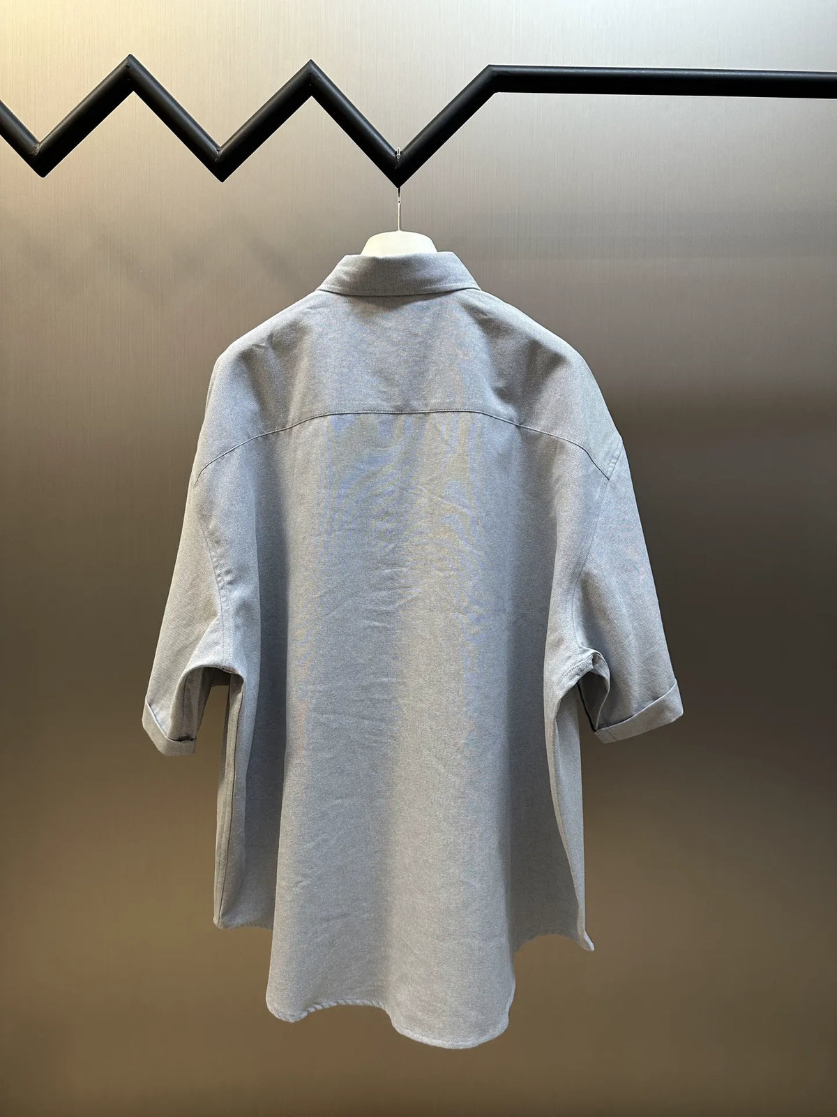 Light gray short-sleeve button-up shirt, back view with curved hem