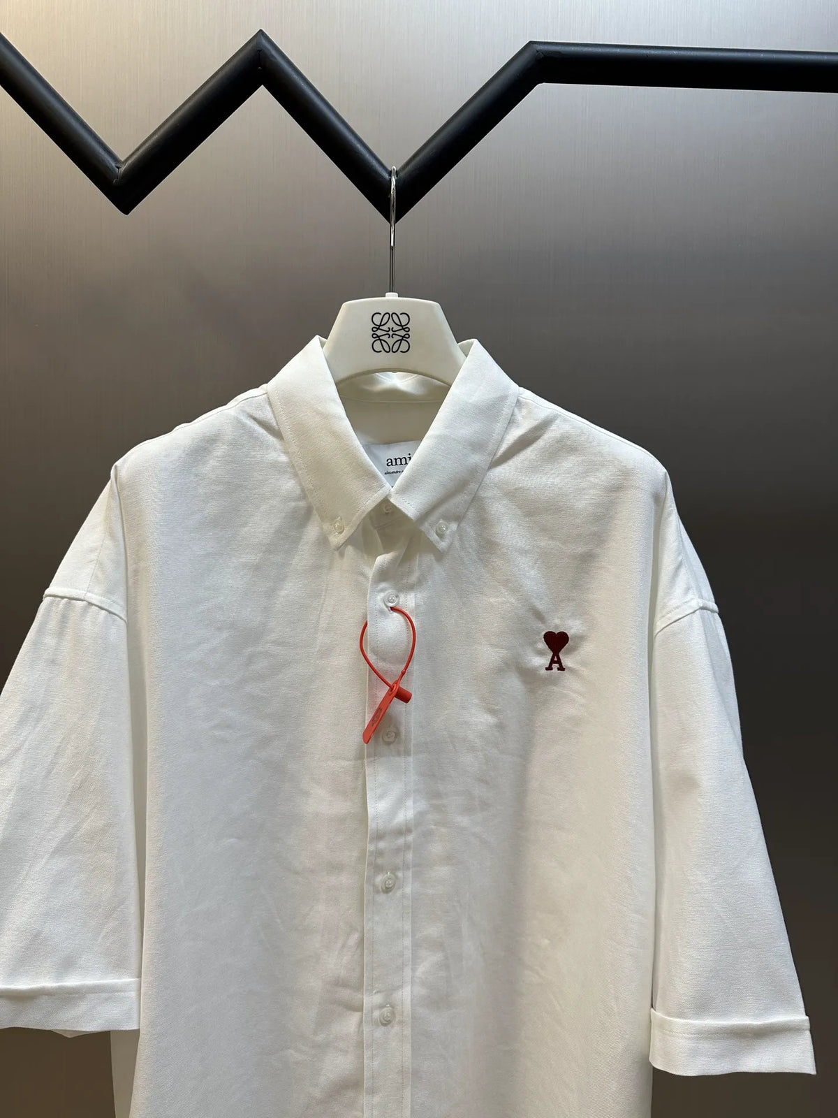 White short-sleeve button-up shirt with collar, chest logo, and red ribbon tie