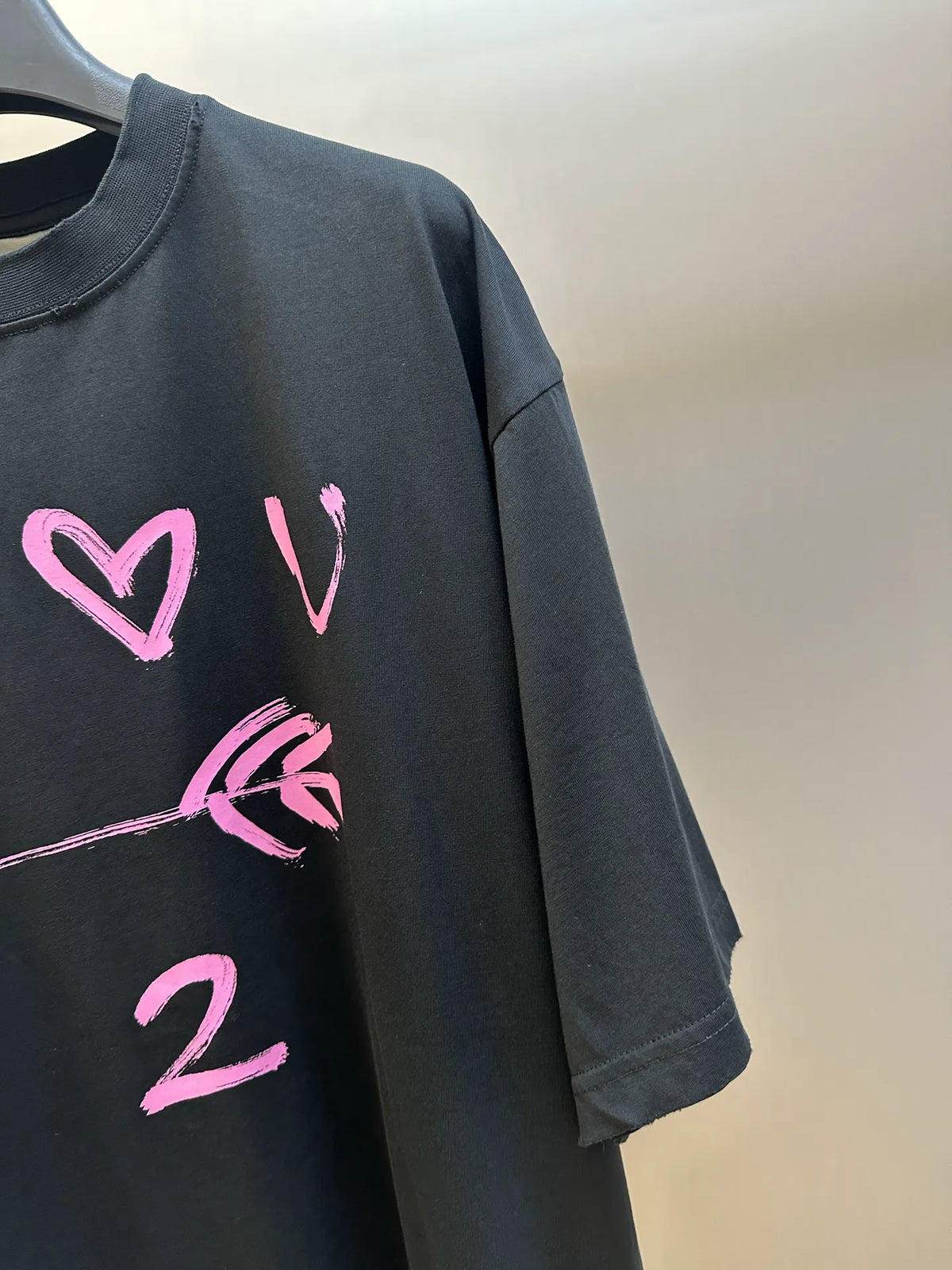 Black T-shirt sleeve and front print with pink heart and “2” graphic