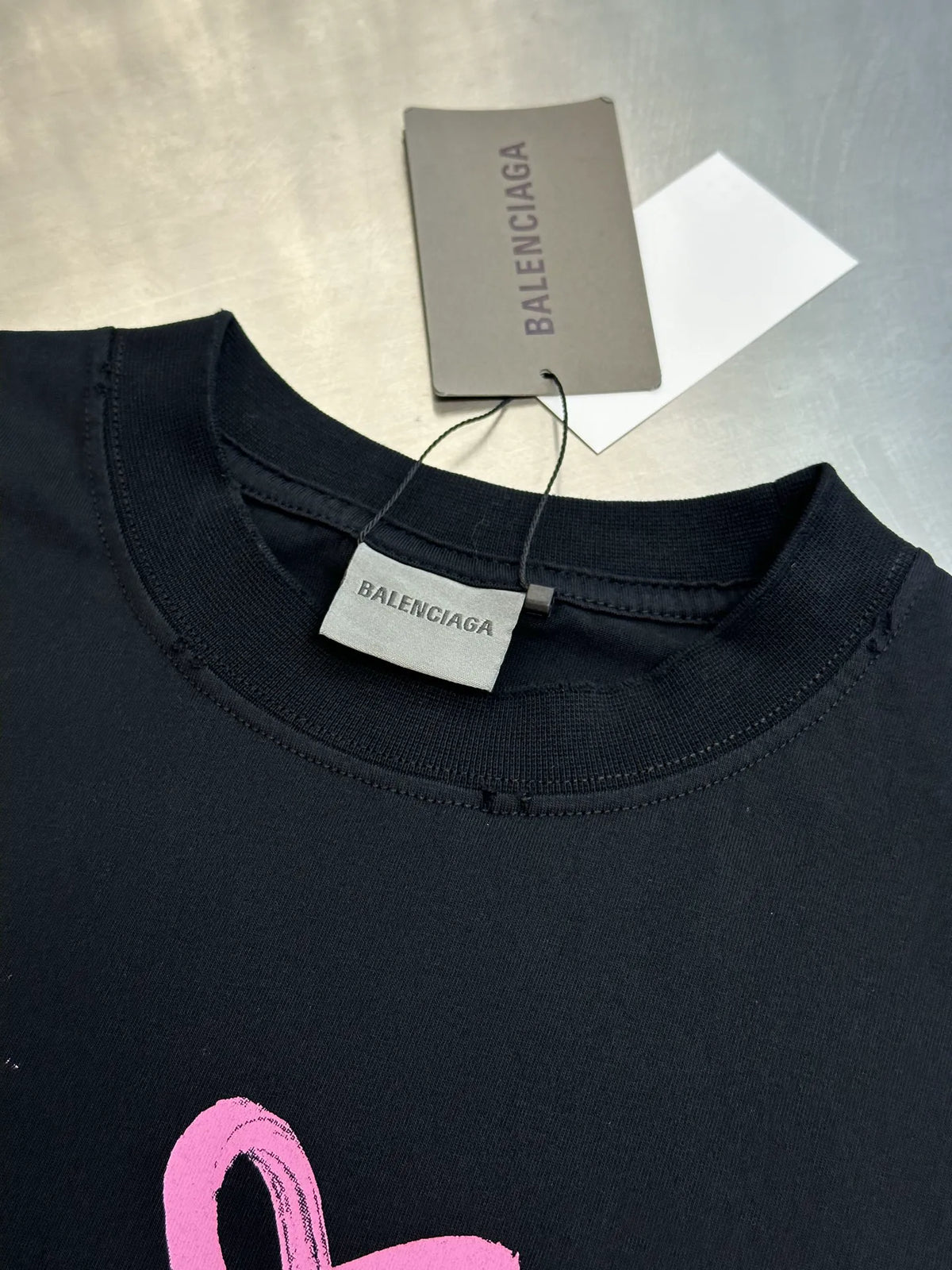 Black crewneck T-shirt neckline with brand tag and pink graphic print