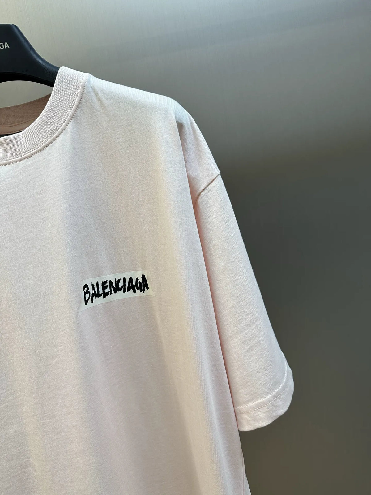 Balenciaga light pink T-shirt with black logo print on the chest.