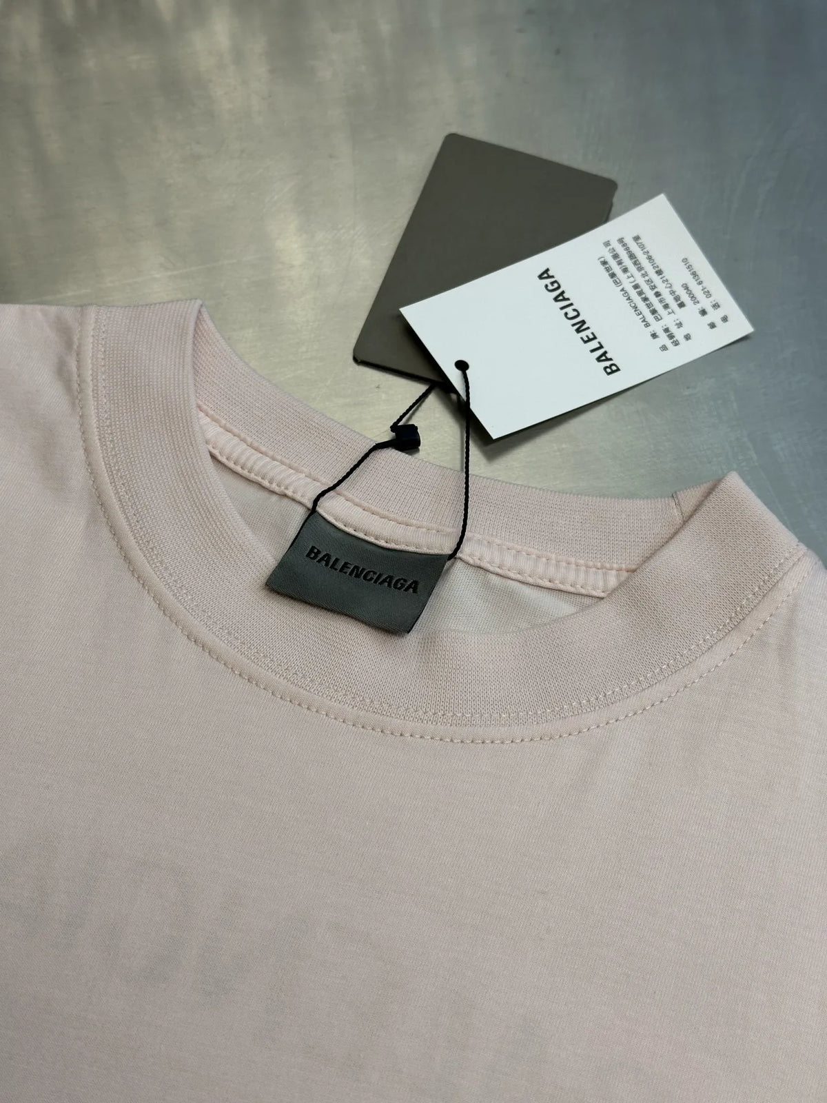 Balenciaga light pink T-shirt neckline with size tag and hanging label.