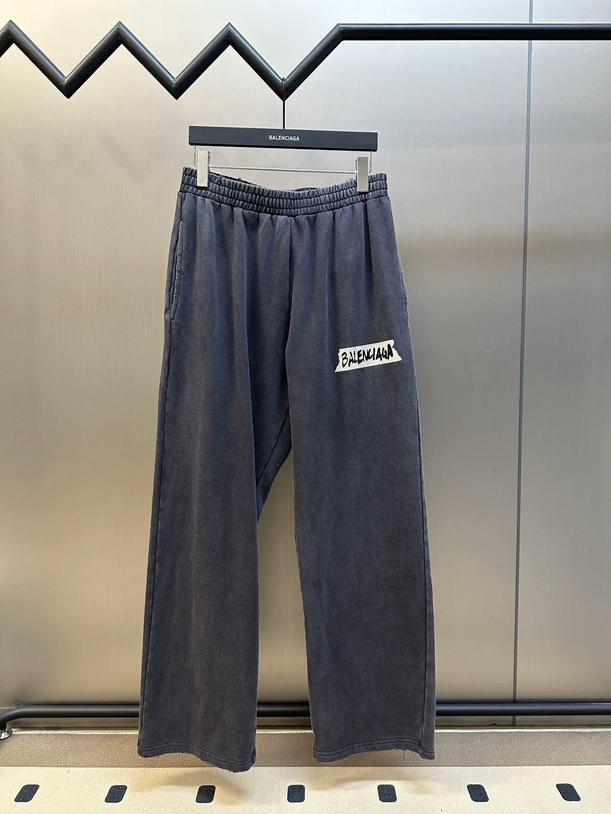Dark blue Balenciaga pants with elastic waistband, relaxed wide legs, side logo patch
