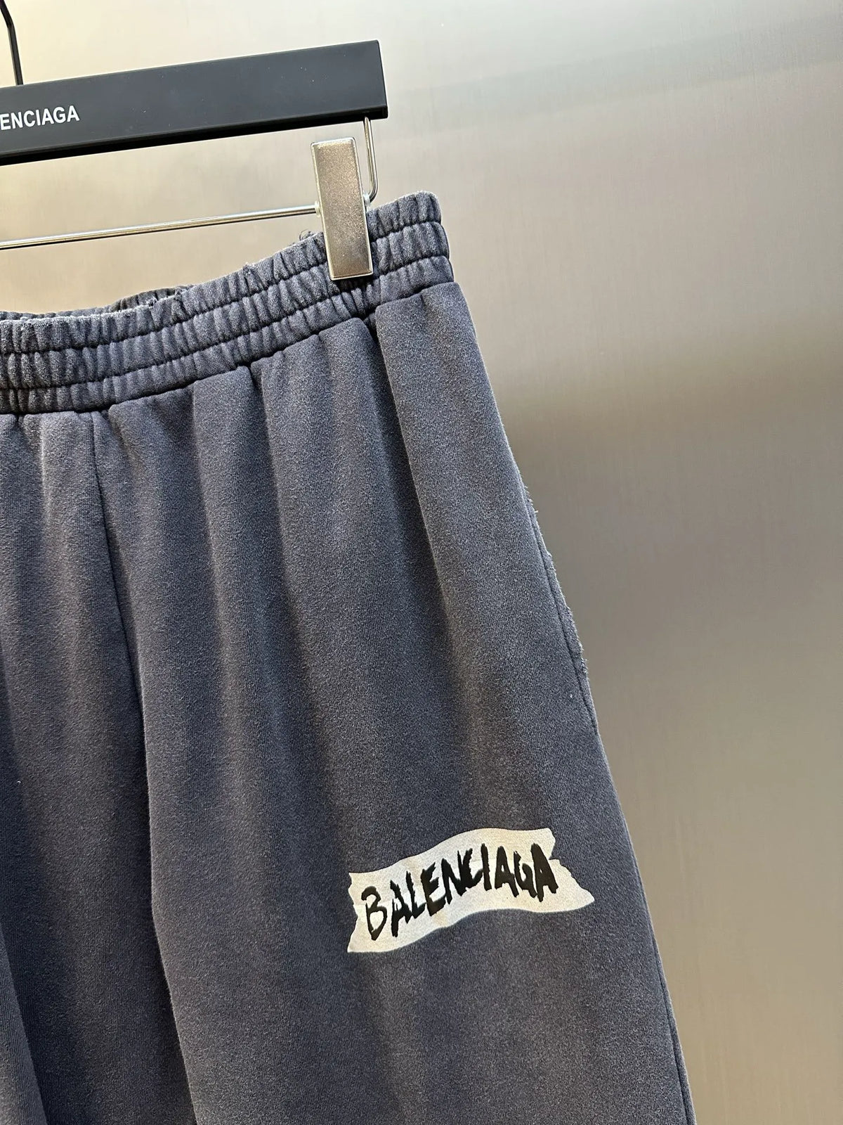 Close-up of dark blue pants leg with white Balenciaga logo patch
