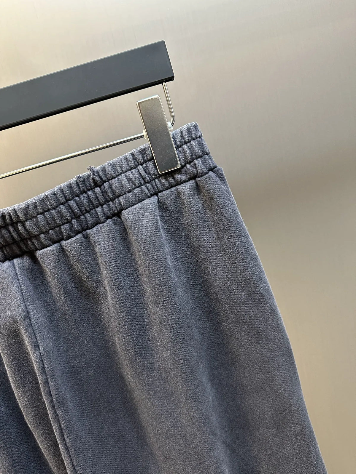 Dark blue pants waistband with elastic gathered trim and adjustable hanging tag