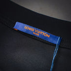 Interior neck label on black long-sleeve top with blue “LOUIS VUITTON” text