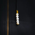 Black hoodie zipper close-up with gold teeth and pearl pull charm
