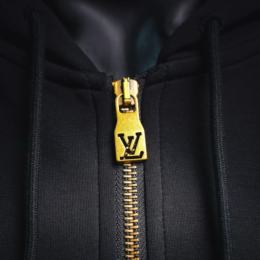 Gold zipper pull with LV emblem on black hoodie