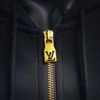 Gold zipper pull with LV emblem on black hoodie