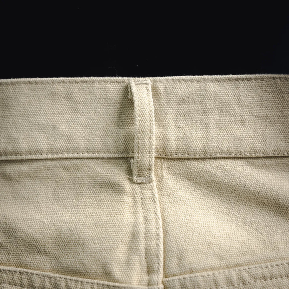 Light beige pants fabric close-up with waistband seam