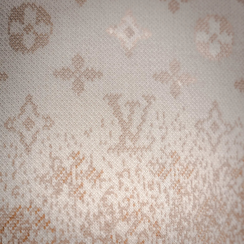 Close-up of cream knit fabric with scattered LV monogram motifs.