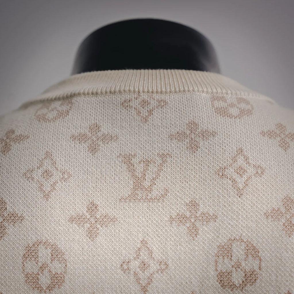 Crew neck ribbed collar of cream sweater with LV monogram pattern.