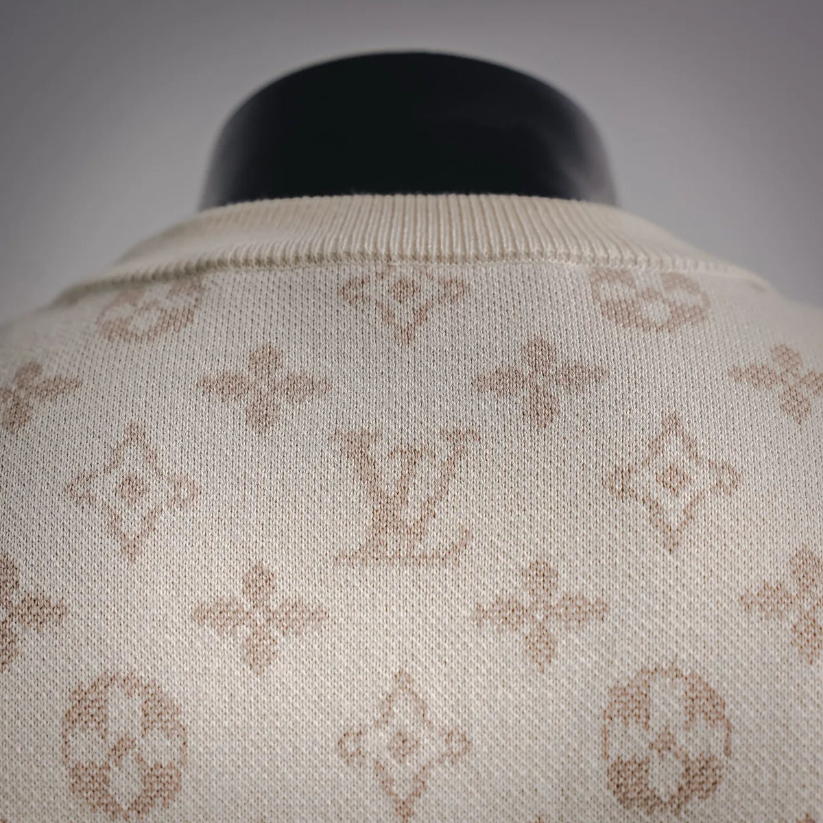 Crew neck ribbed collar of cream sweater with LV monogram pattern.