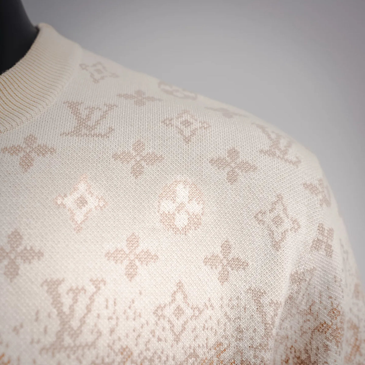 Shoulder close-up of cream sweater with LV monogram jacquard texture.