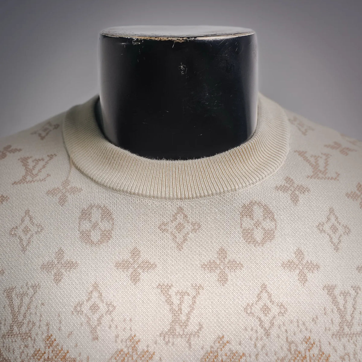 Ribbed crew neck on beige sweater with repeating LV monogram pattern.
