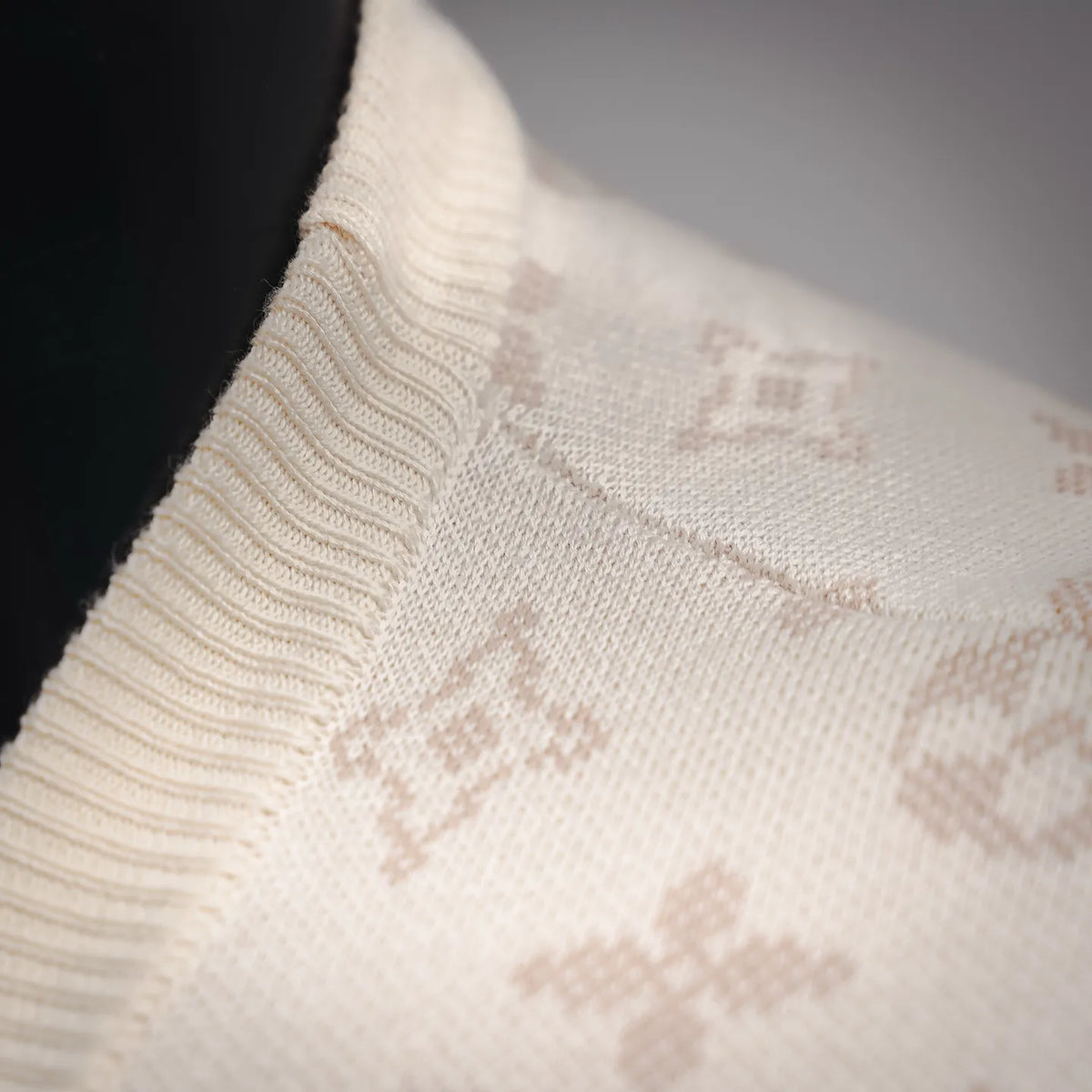 Ribbed knit sleeve edge on cream sweater with LV monogram motifs.