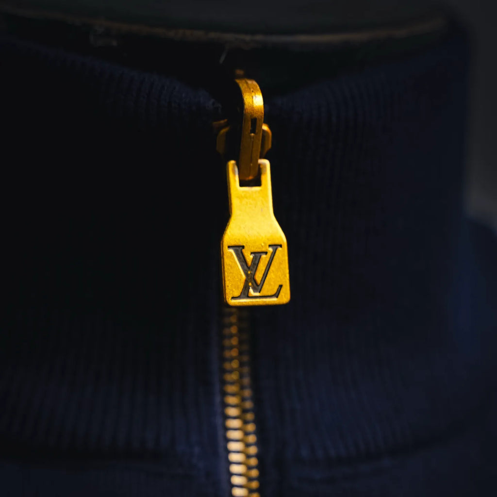 Gold zipper pull with LV emblem on navy zip-up coat