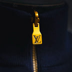 Gold zipper pull with LV emblem on navy zip-up coat