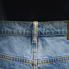 Light blue denim waistband with orange topstitching and reinforced center seam