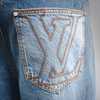 Light blue denim back pocket with orange LV-style embroidery and double-row stitching