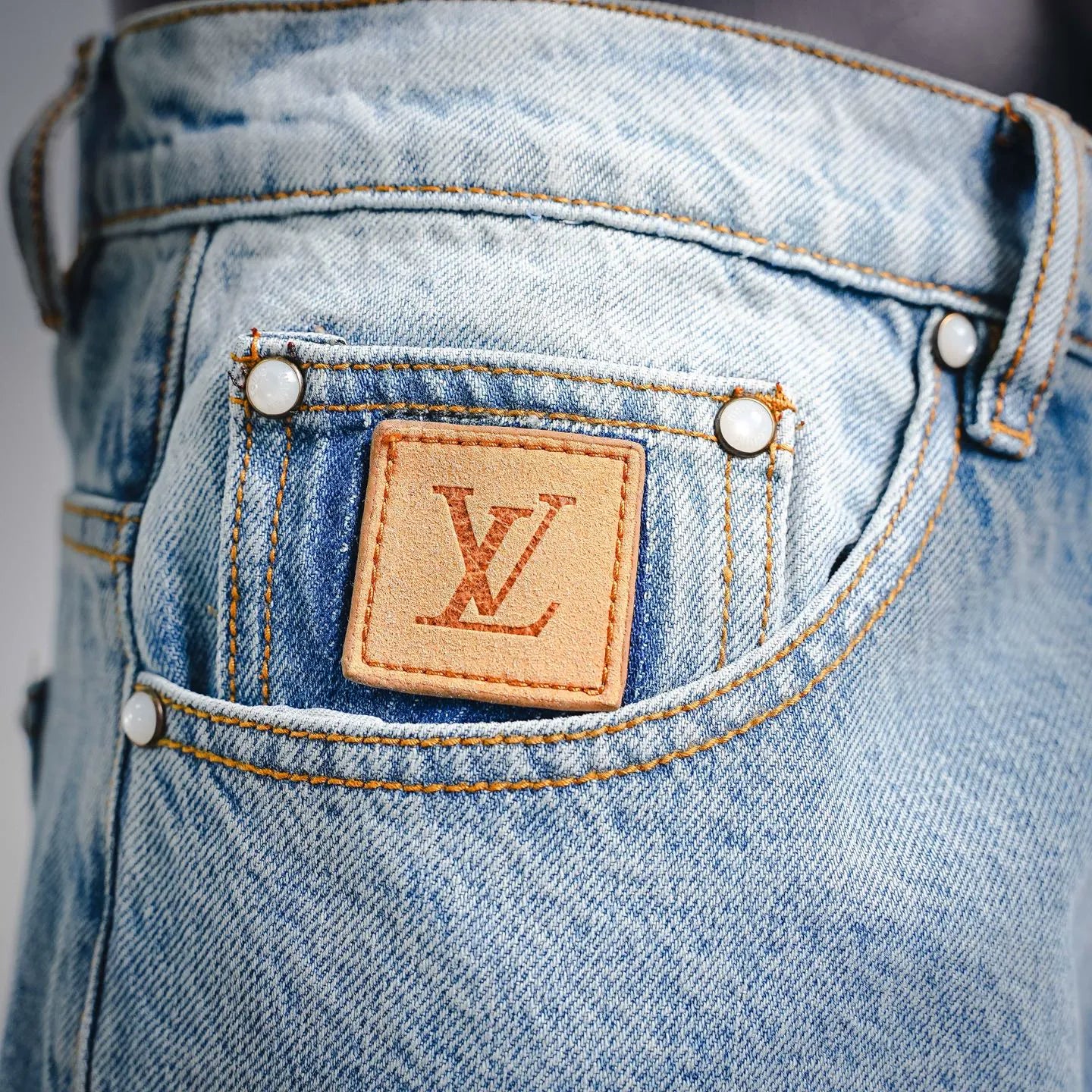 Light blue denim front waistband with tan LV leather patch and gold button rivets