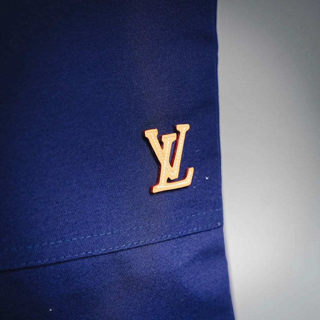 Blue shorts-style pants with gold Louis Vuitton logo patch on leg