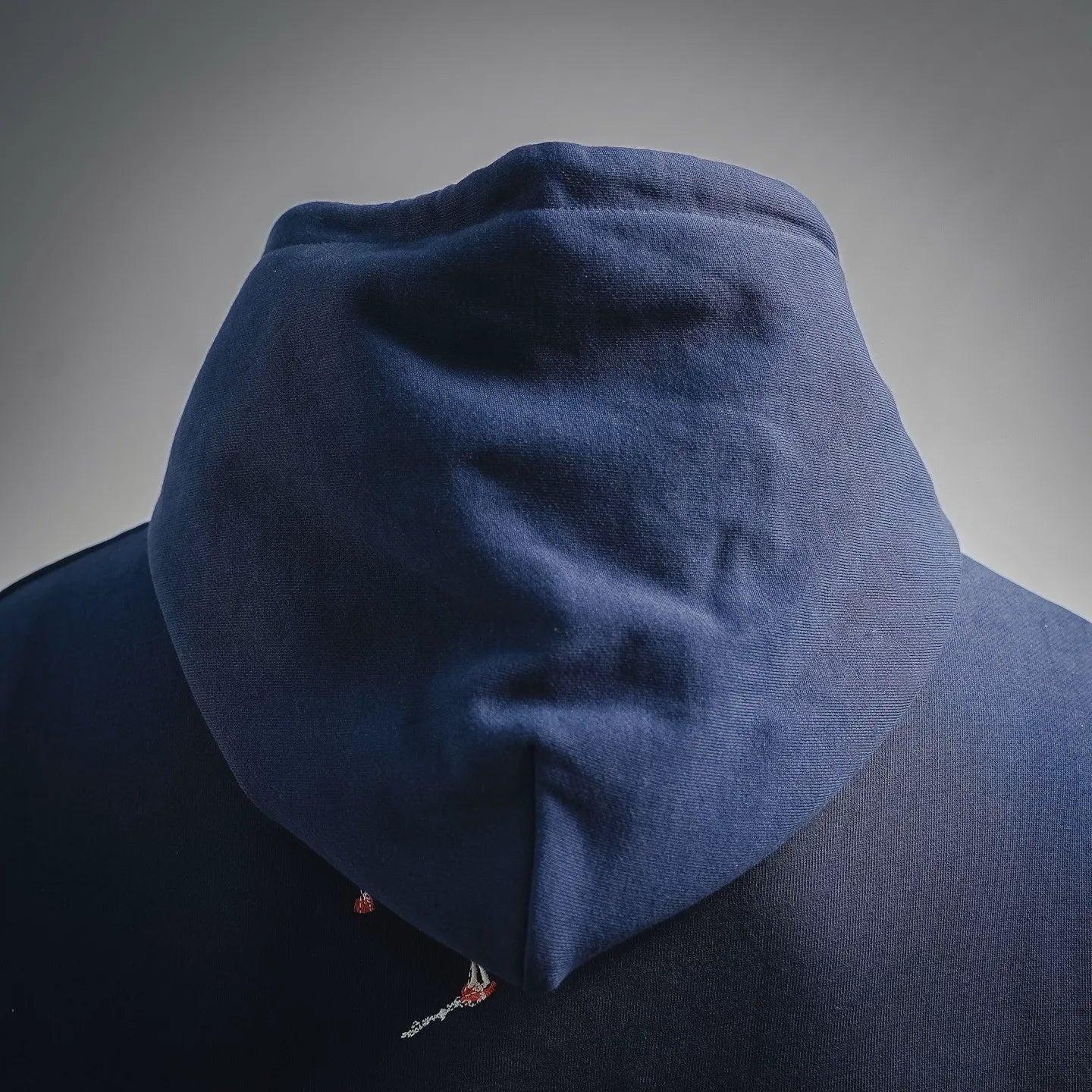 Navy hoodie hood with small embroidered detail near lower back