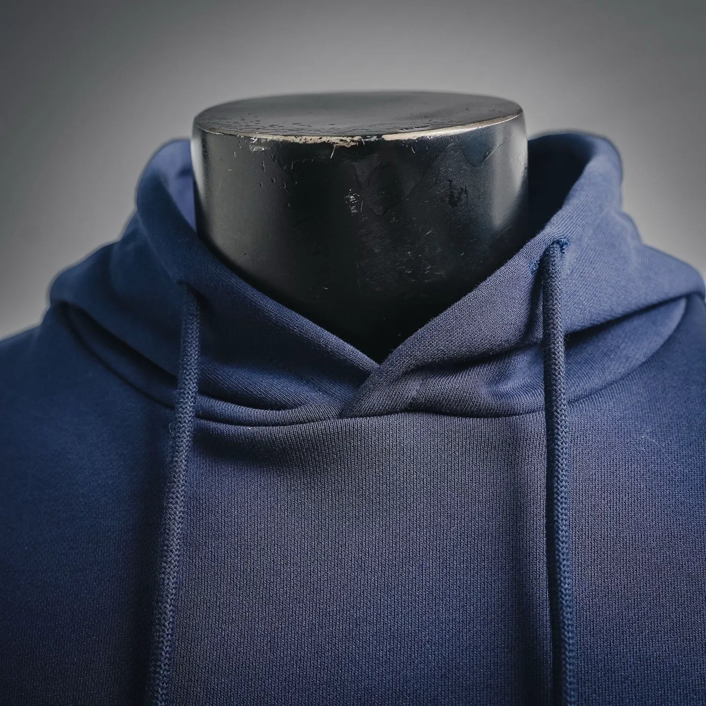 Navy hoodie close-up at hood and neckline with drawstring openings