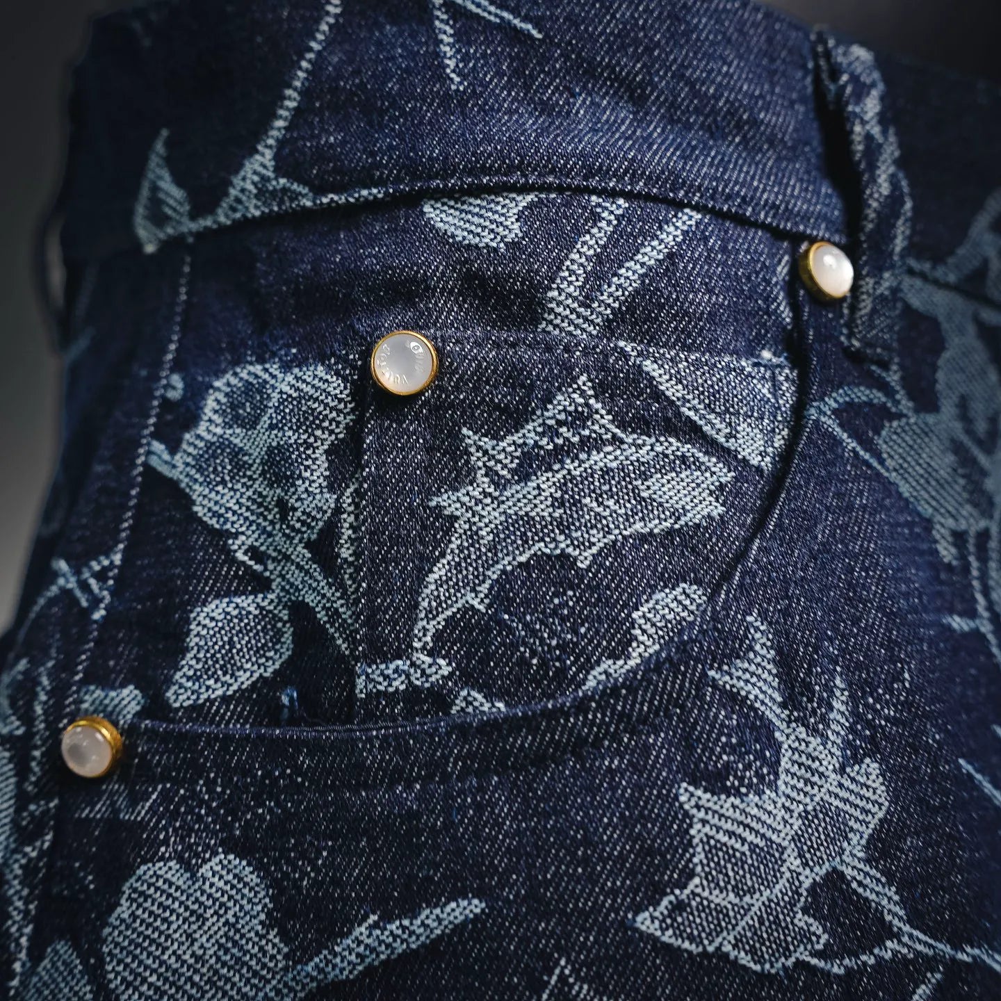 Floral-print dark denim pants with gold buttons at waistband