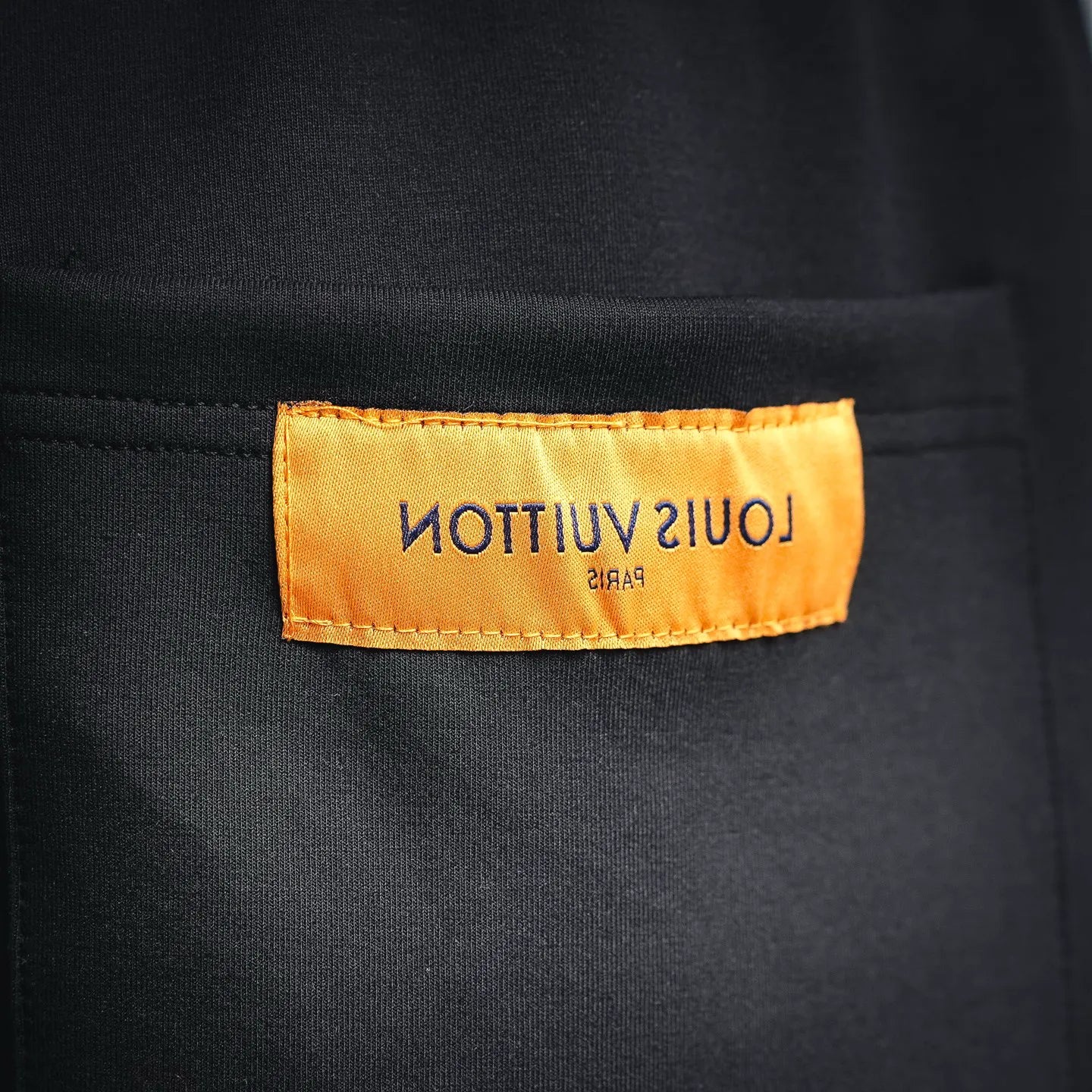 Black shorts with orange inner label reading 'LOUIS VUITTON'